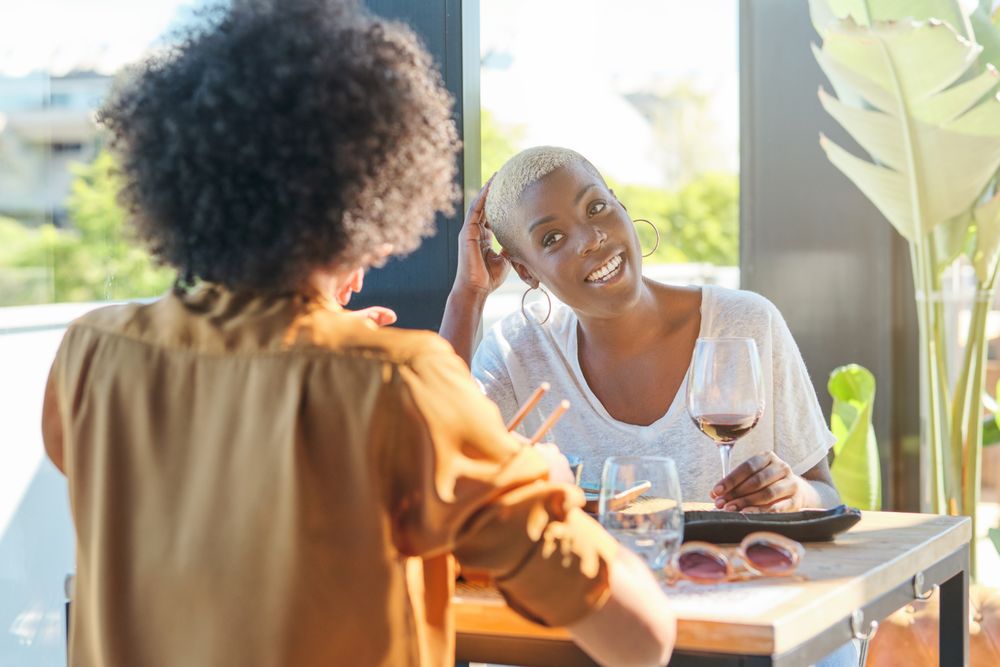 Smiling Black women with glass of wine in cafe