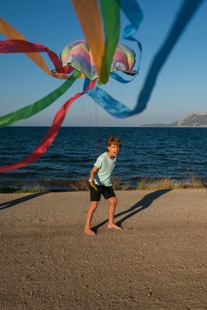 Excited kid with flying kite on beach