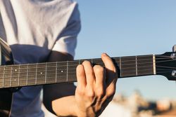 young man sitting playing acoustic guitar close-up