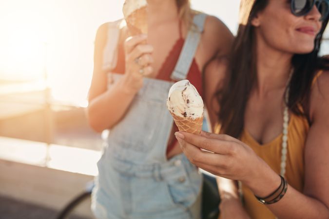 Close up shot of ice cream in hand of a woman standing with her friend