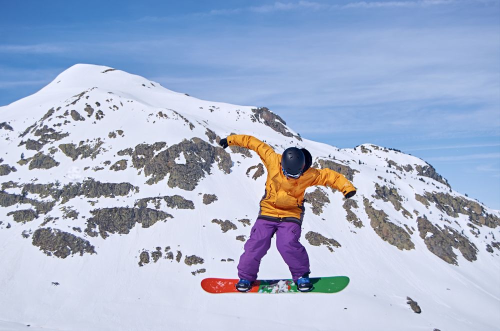 Unrecognizable snowboarder jumping on slope