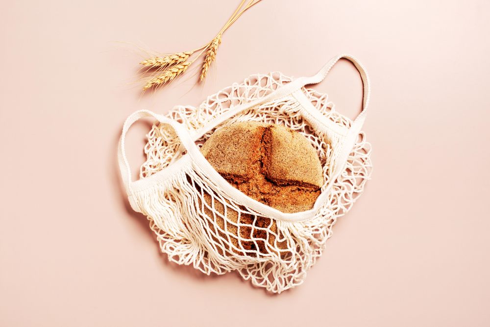 Top view of baked organic rye bread in mesh bag with wheat grass