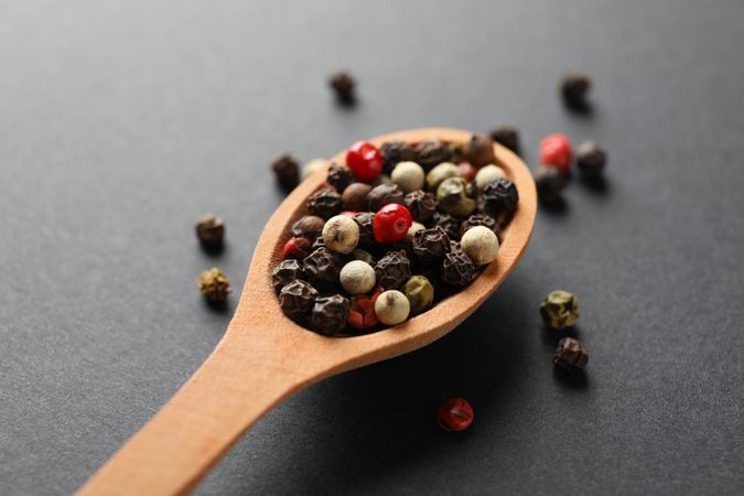 Top view of wooden spoon filled with multi-colored peppercorn