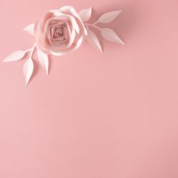 Paper rose flower, leaves and petals on pink background