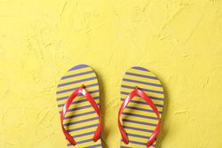 Flip flops on color background, space for text and top view. Summer vacation backdrop