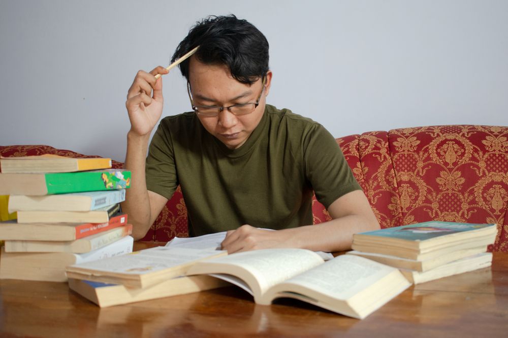 Asian young male reading book with frustrated gesture