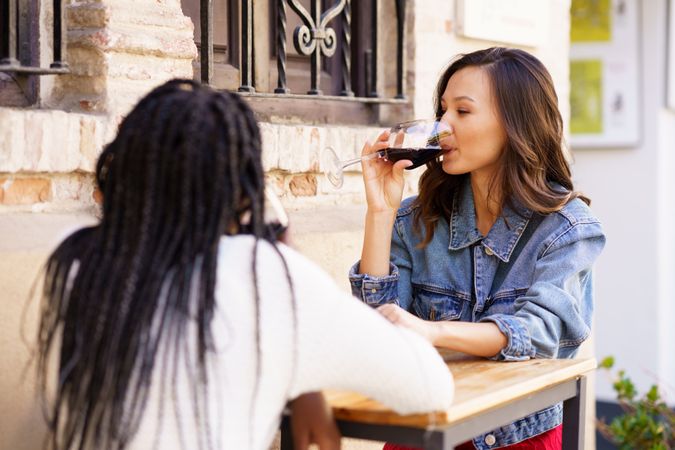 Young friends sipping red wine at an outdoor table at a restaurant