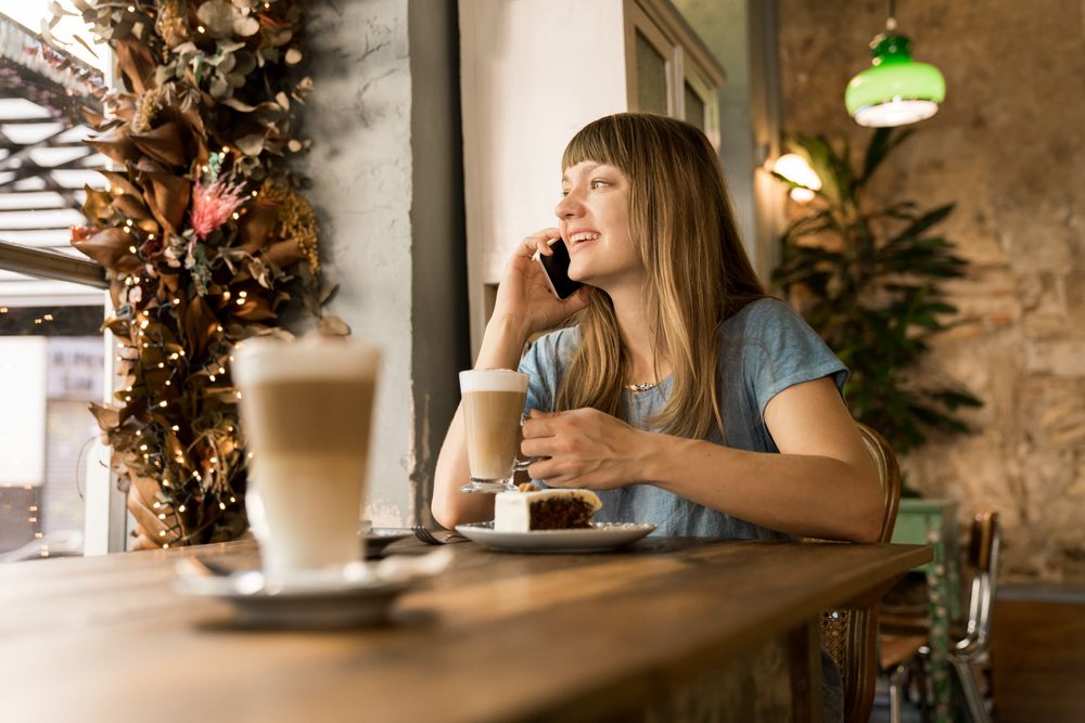 Cheerful woman talking on phone in cafe