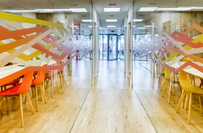 Interior of light corridor among glass walls in modern office with colorful furniture
