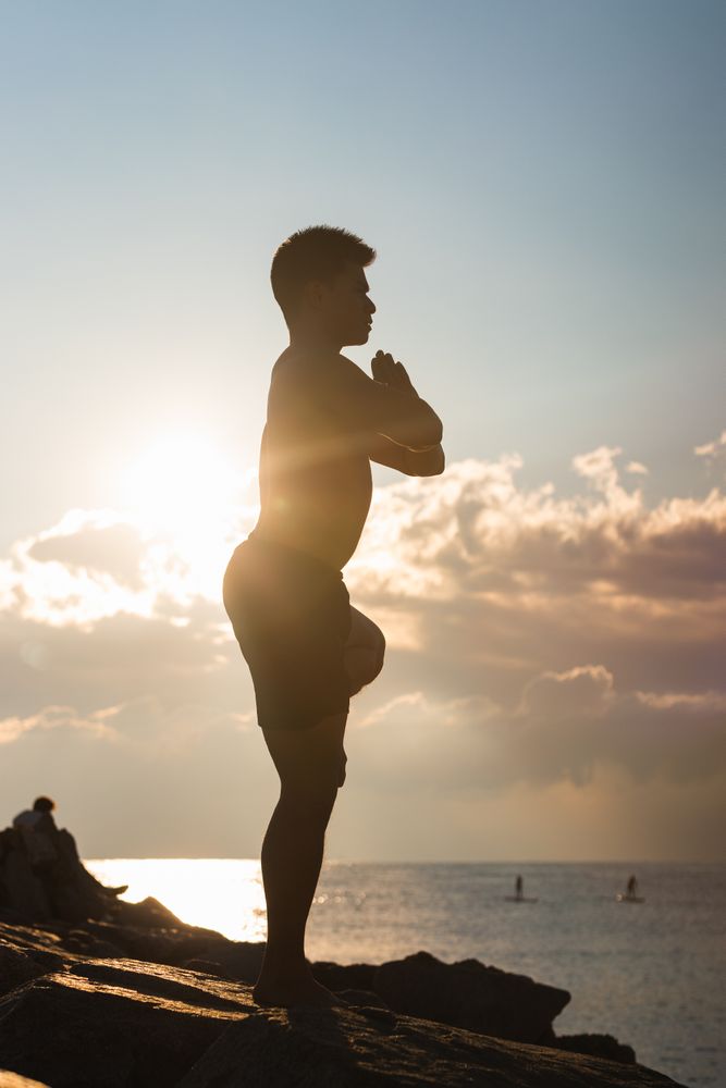 Man practicing yoga asana at sunset