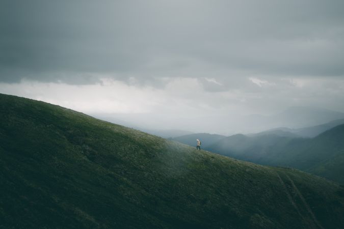 Anonymous traveler walking on path on hillside