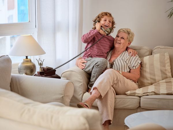 Laughing boy answering telephone call while resting grandmother