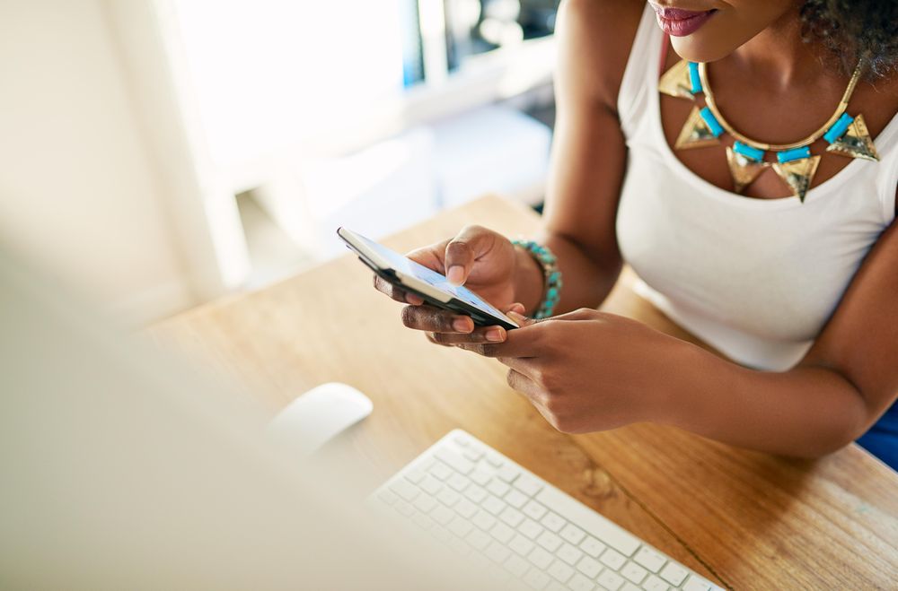 Looking down at Black female using cell phone at desk