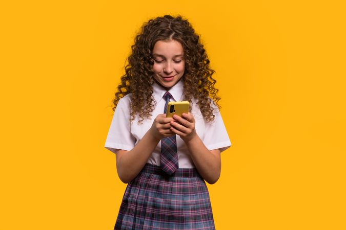 Girl using smartphone, focused expression, school attire.