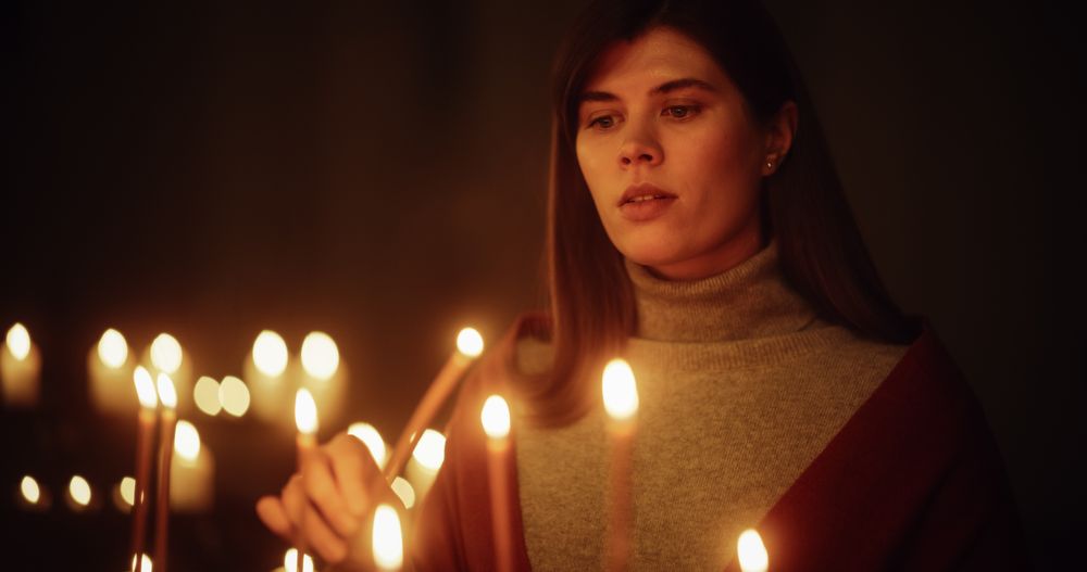 Aesthetic Shot of Young Christian Woman Lighting a Candle in Church, Praying and Expressing Devotion to the Lord.