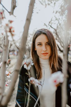 Young happy woman between trees in garden