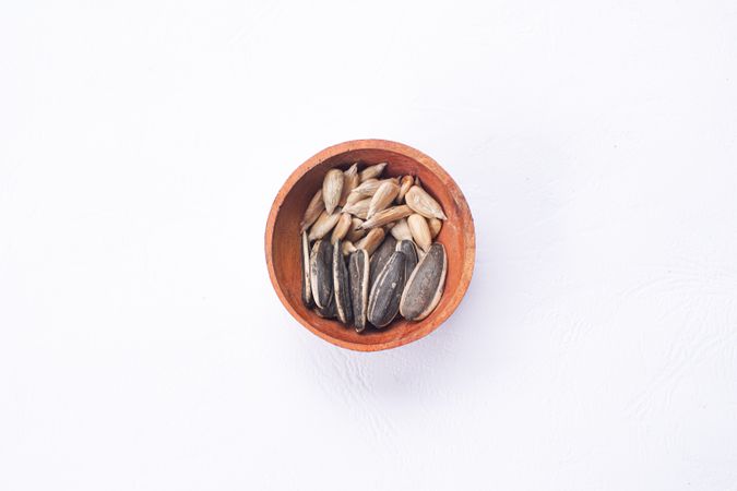 Sunflower seeds in wooden bowl and wooden spoon on table
