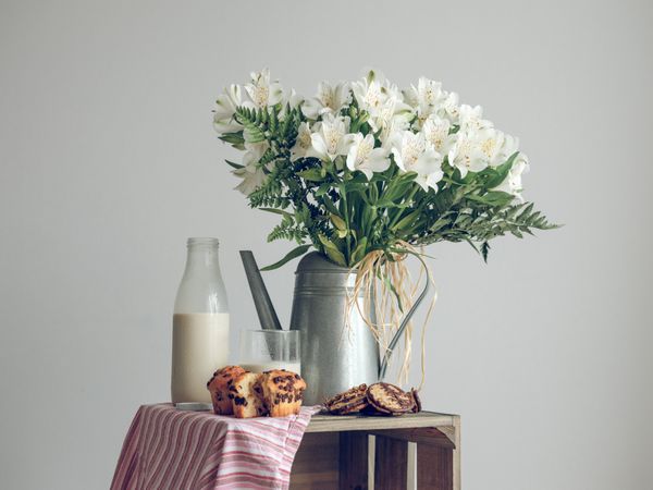 Rustic composition of flowers with milk and pastry