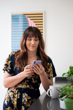 Female in floral print dress checking smartphone