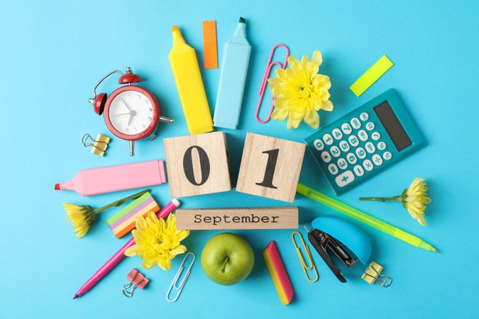 Wooden calendar with 1 september and school supplies on blue background