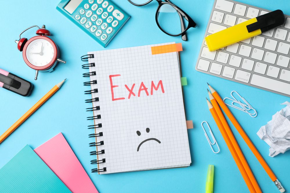 Top view of exam notebook with drawn sad face on blue background