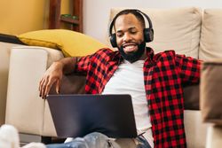 Black man in casual clothes using laptop at home.