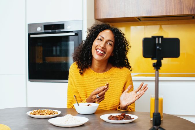 Woman in colorful kitchen presenting her breakfast on a livestream