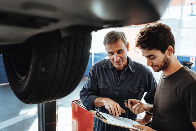 Two people working in auto garage and making a list of problems in the vehicle
