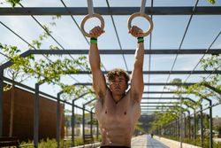 Strong young sportsman exercising with rings