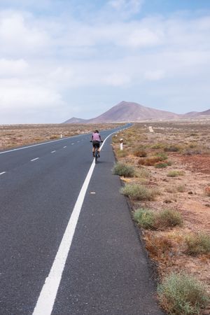 Back of woman biking on quiet road
