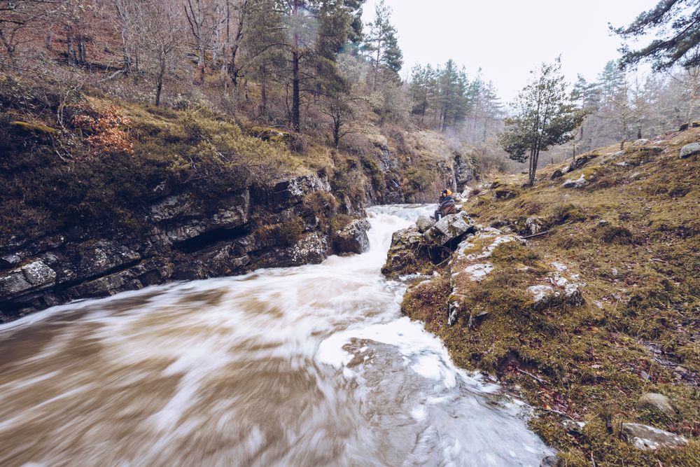Woman gazing at fast mountain river in forest