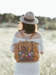 Female traveller with colorful backpack walking on field