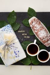 inscription of new year on a board with gift, muffins and coffee