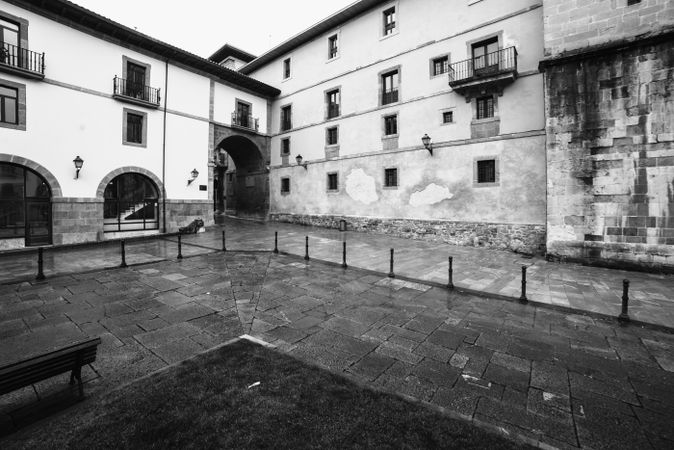 Court with lawn and bench between old buildings