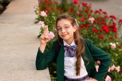 Girl in school uniform smiling and raising finger