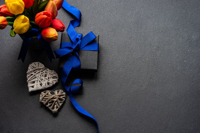 Present with blue ribbon with fresh tulips and heart ornaments