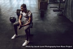 Athlete relaxing after workout sitting on a bench in the gym 4d6XQ0