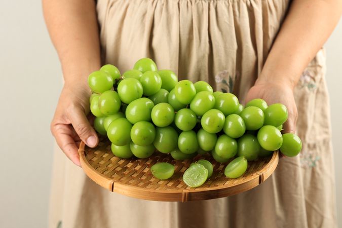 Female Hands Holding a Bunch of Shine Muscat Green Grape