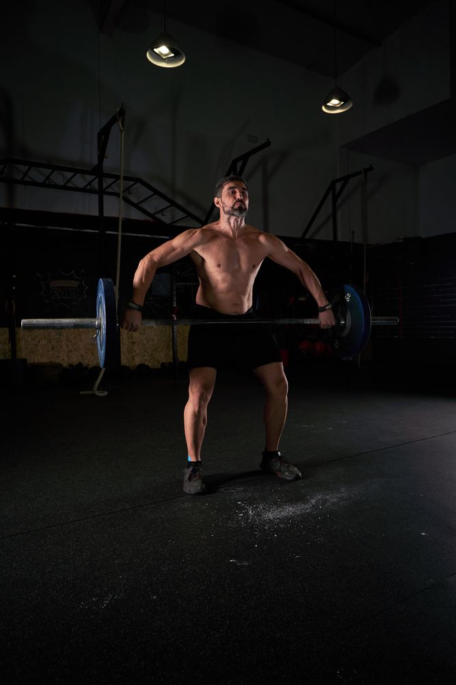 Muscular professional male athlete lifting barbell with weights