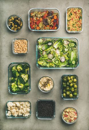 Variety of vegetable dishes arranged in glass containers, vertical composition