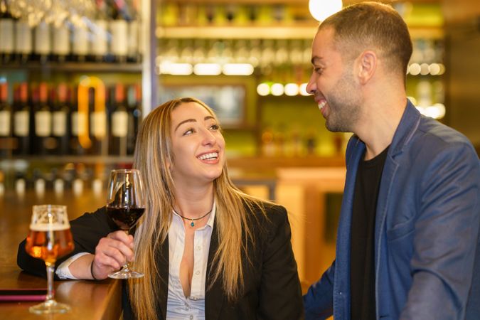 Man and woman laughing and smiling over beer and wine at a bar or lounge