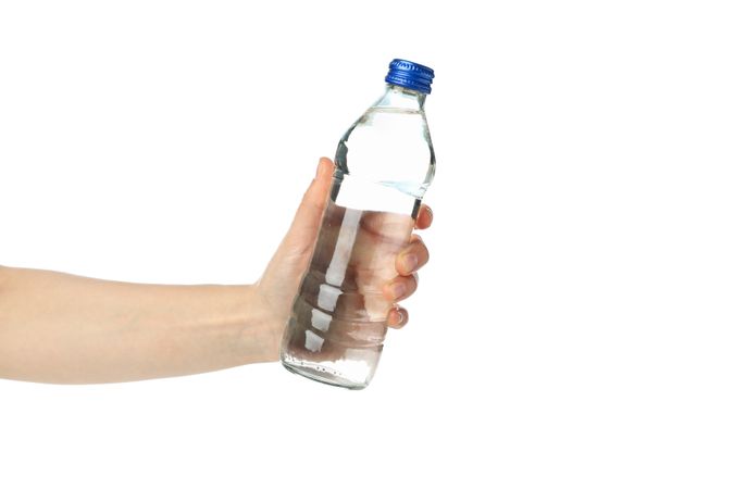 Person holding plastic water bottle in plain room