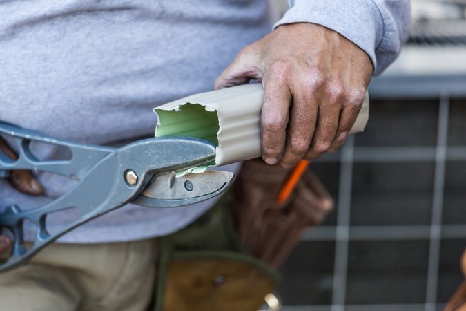 Worker Cutting Aluminum Rain Gutter With Heavy Shears