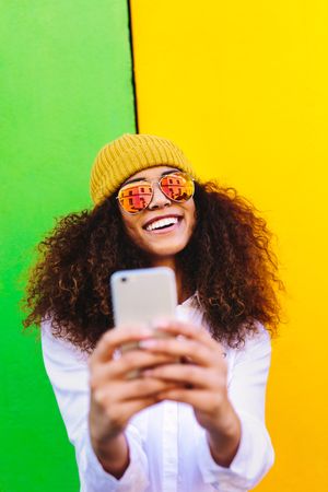Young woman wearing reflective sunglasses and taking selfie