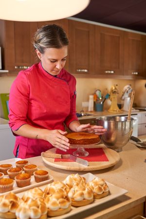 Professional female confectioner assembling cake at home
