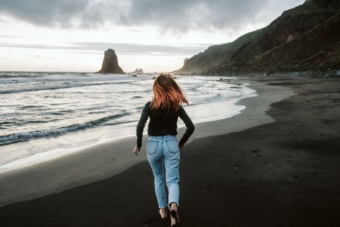 Barefoot female running near waving sea