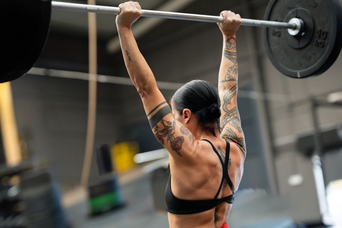 Rear view of a strong fit woman lifting barbell