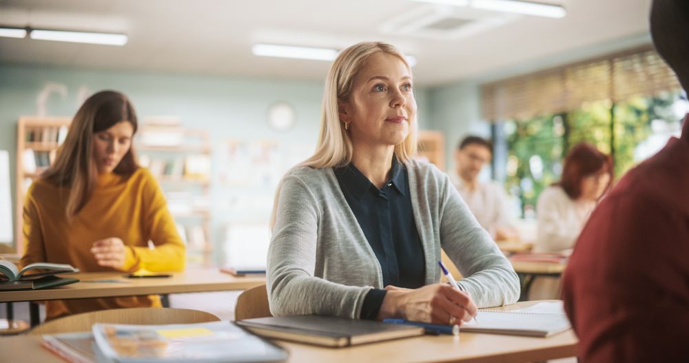 Diverse Mature Students Learning in Classroom, Reading Textbooks and Writing in Notebooks