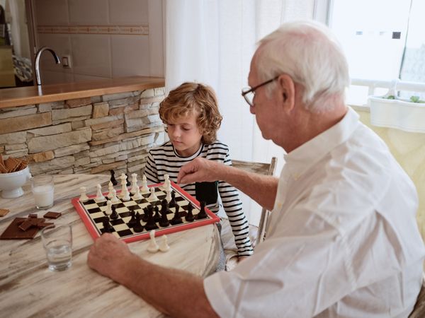 Grandfather and grandson playing chess at home
