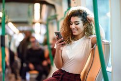 Arab woman sitting in train carriage checking phone